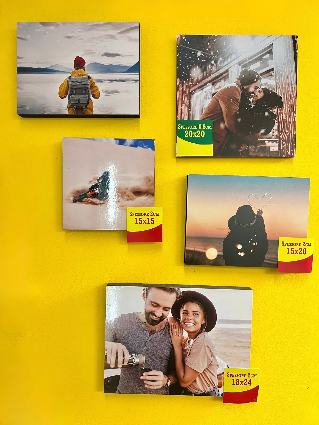 Pannelli fotografici di vari formati e spessori appesi su una parete gialla